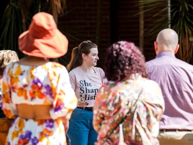A tour guide speaking to a group of people outdoors.