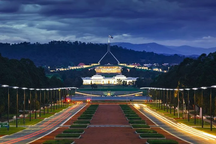 Wide shot of Parliament House illuminated at dusk.