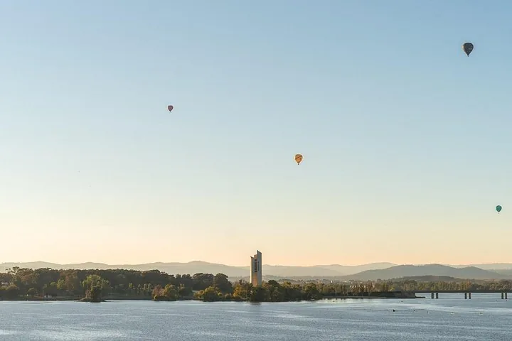 Heißluftballons über einem See mit dem Carillon-Turm.