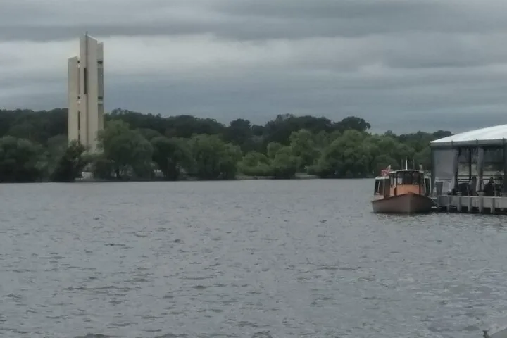 A boat on a lake with a tower in distance.